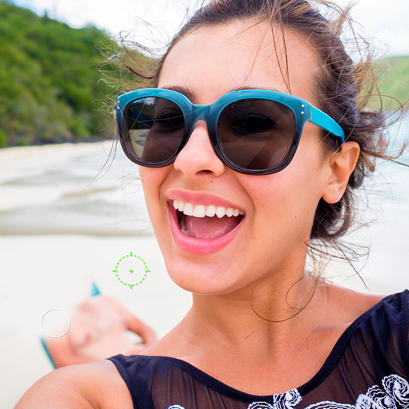 Smiling woman on beach with man in background being erased using PicMonkey's Clone tool. 