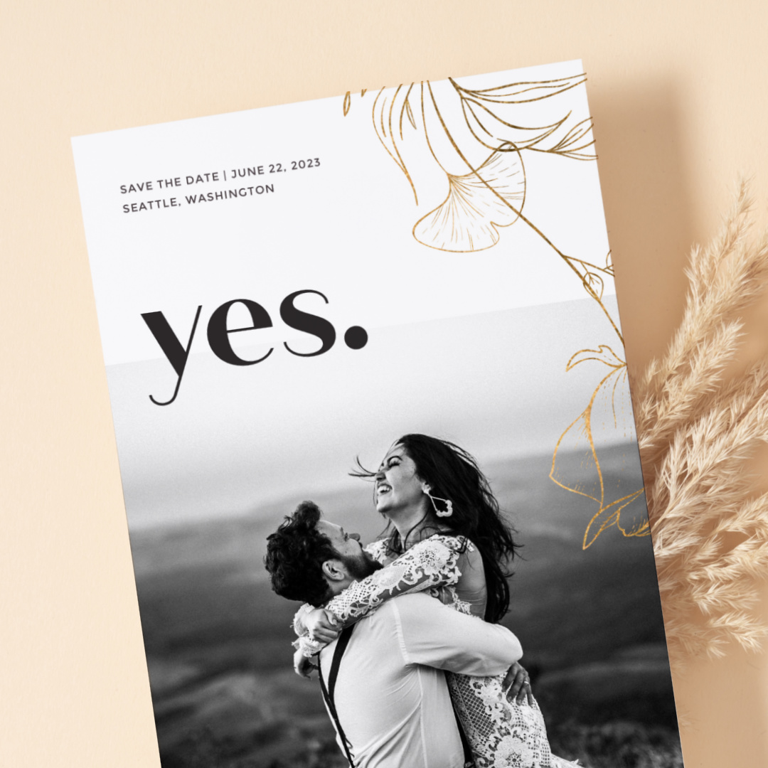 Photo wedding invitation example atop strands of wheat and against similarly colored pastel background.