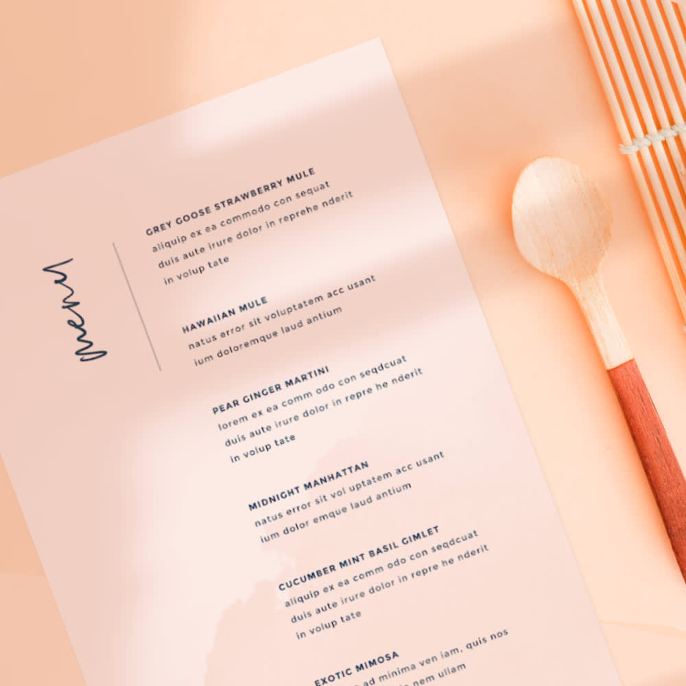 Menu design with spoon next to it, laid against peach colored table.