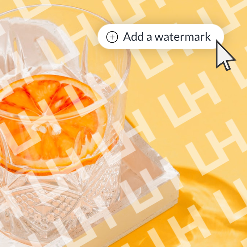 Empty glass with orange slice in it and tiled watermark pattern over entire image, highlighting that you can "Add a watermark" to your designs in PicMonkey. 