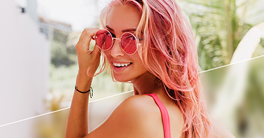 Photo blur effect before and after shot of smiling girl with pink hair and pink sunglasses, half the background blurred and half not.