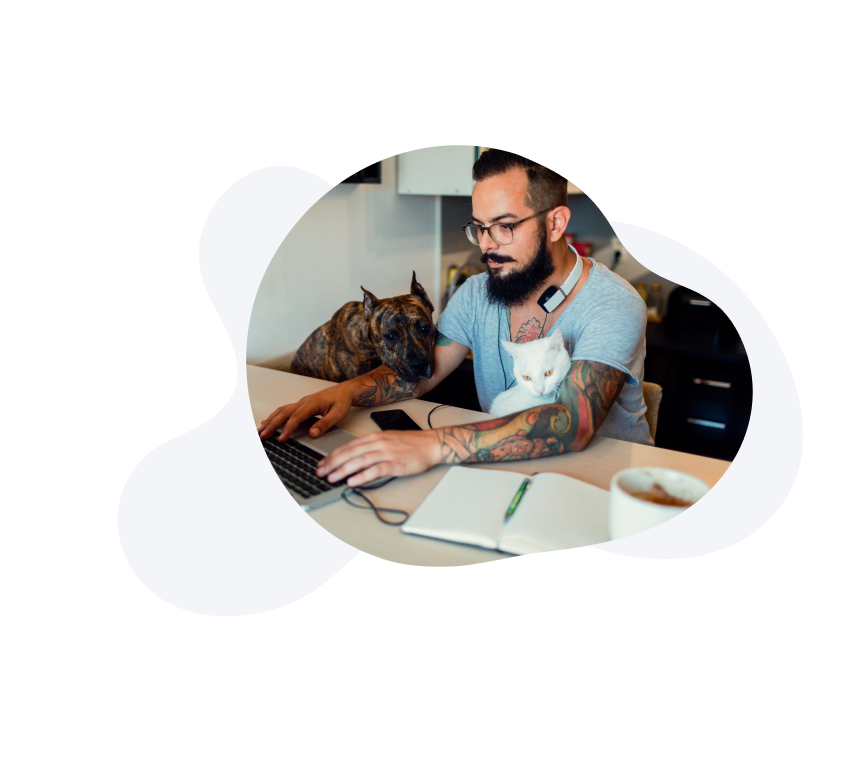 A man working from home with his pet peeking over his arm as he types. 