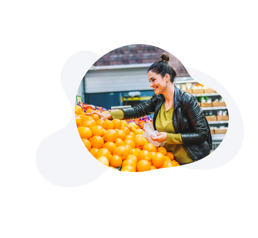 Lady smiling, picking oranges from the supermarket. 