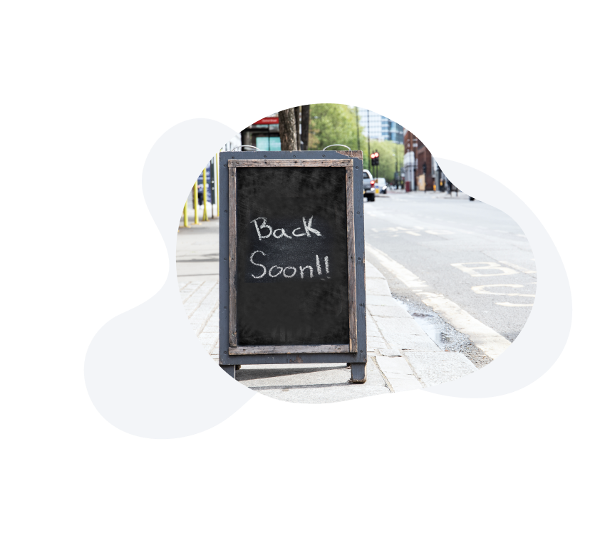 Image of a chalkboard with the message "Back Soon" on the side of the street. 