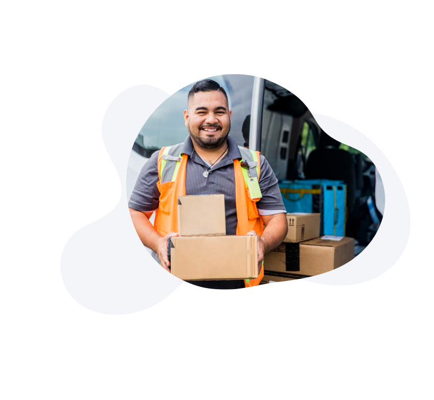 A man holding two boxes, at a courier warehouse. 