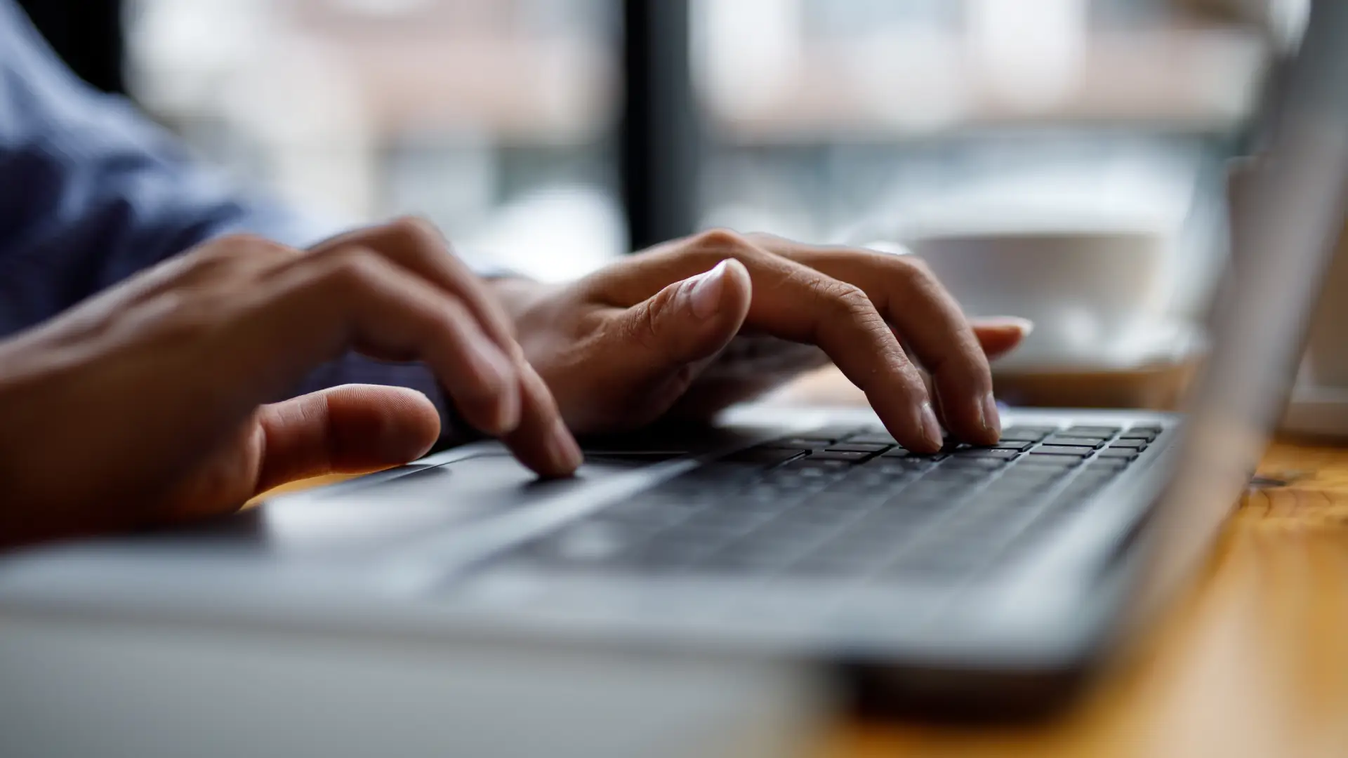 A close-up photo of a person's hands typing on a laptop keyboard