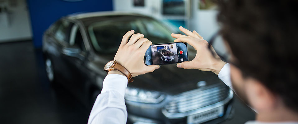 Cars salesman recording a vehicle walkaround video for a prospect 