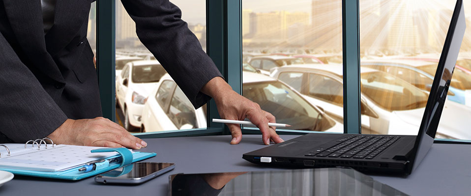 Image of car salesman working in office with new cars in stock.