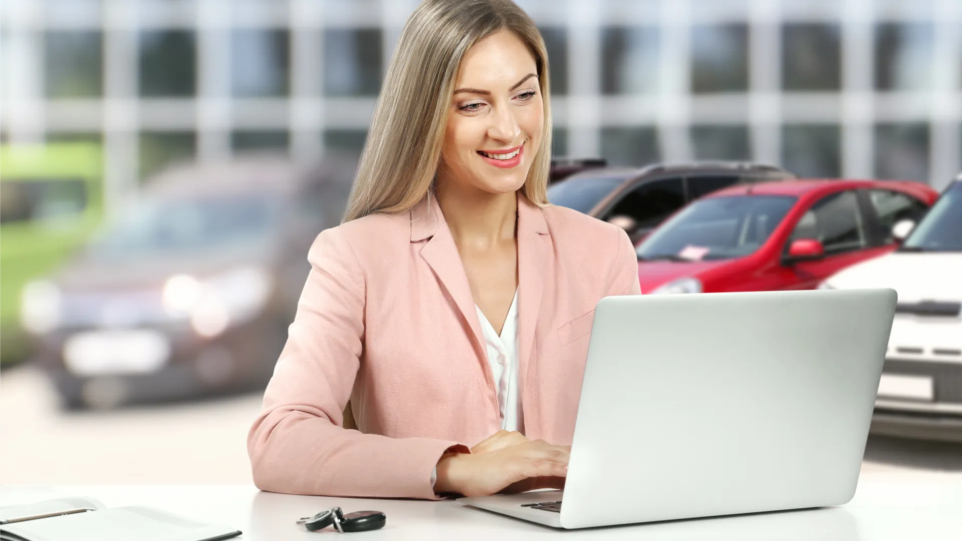 What is lead nurturing for a car dealership thumbnail, a woman in a blazer smiles into her laptop with cars parked behind her outside