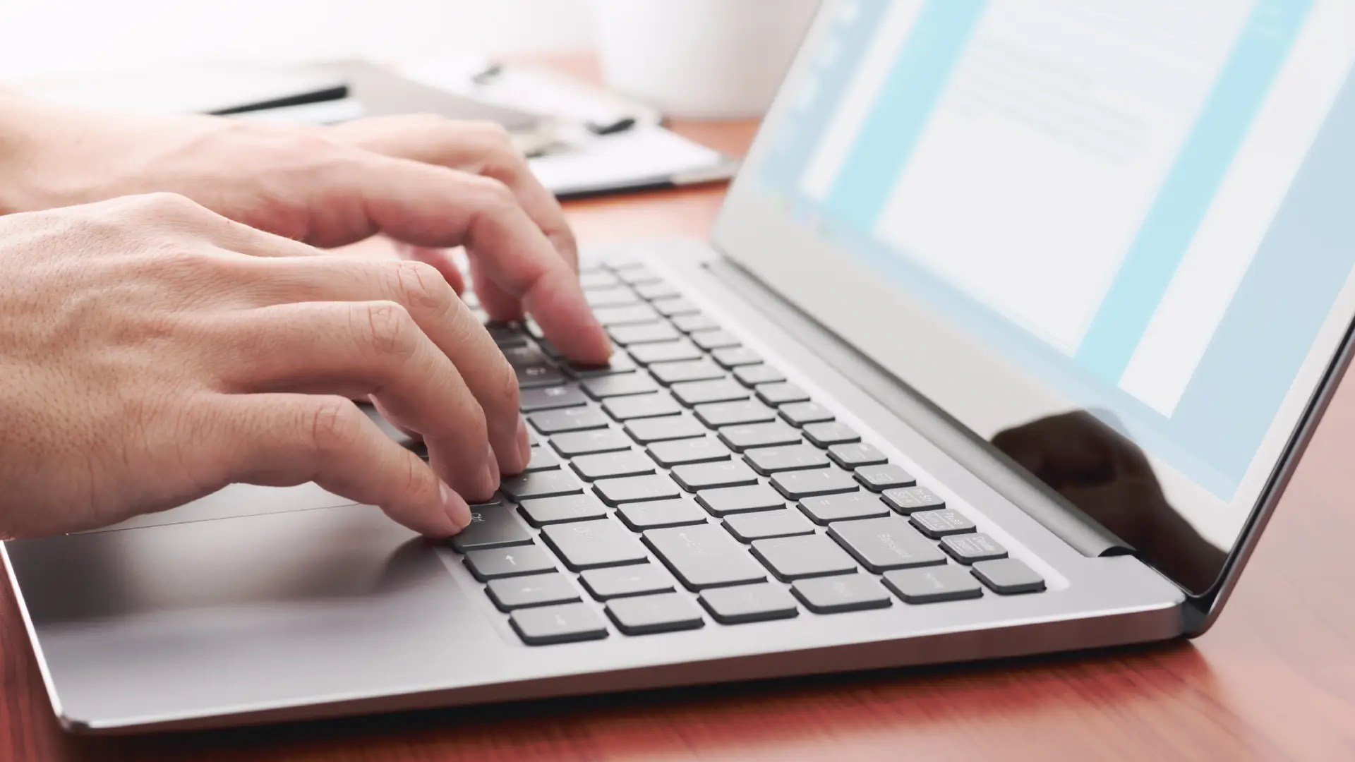 A close-up photo of hands typing on a laptop computer