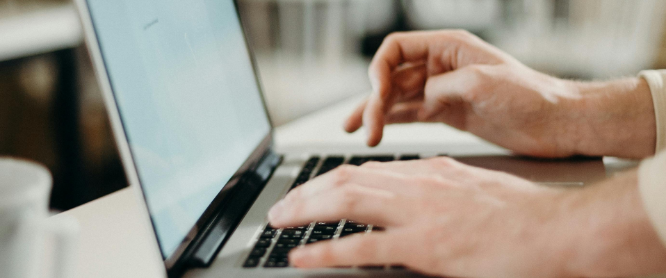 A close-up of a man typing on a laptop keyboard