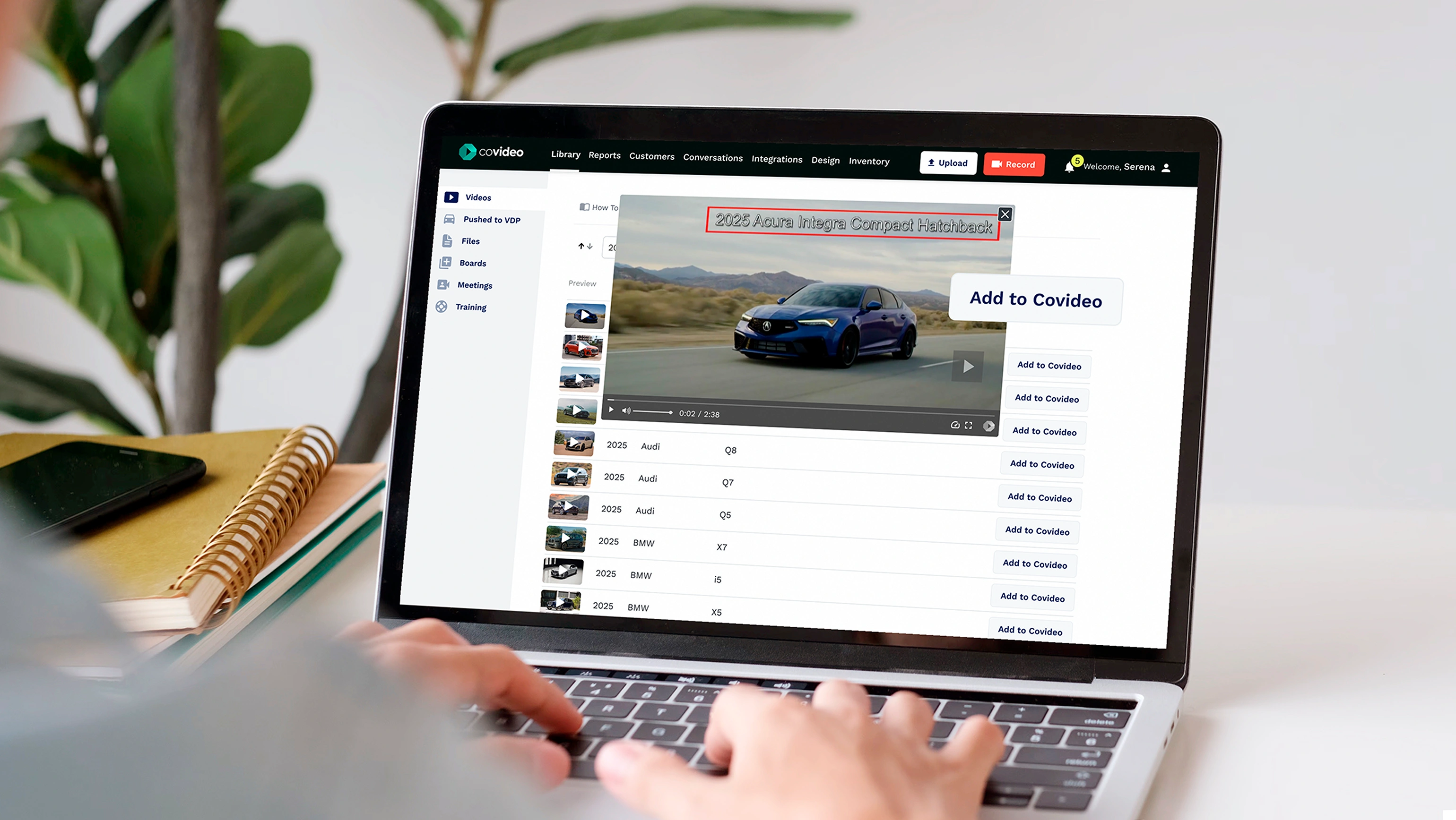 A photo of a person typing on a laptop. On the screen, you can see the Covideo interface and a photo of a car driving on a road open with the words "Add to Covideo."