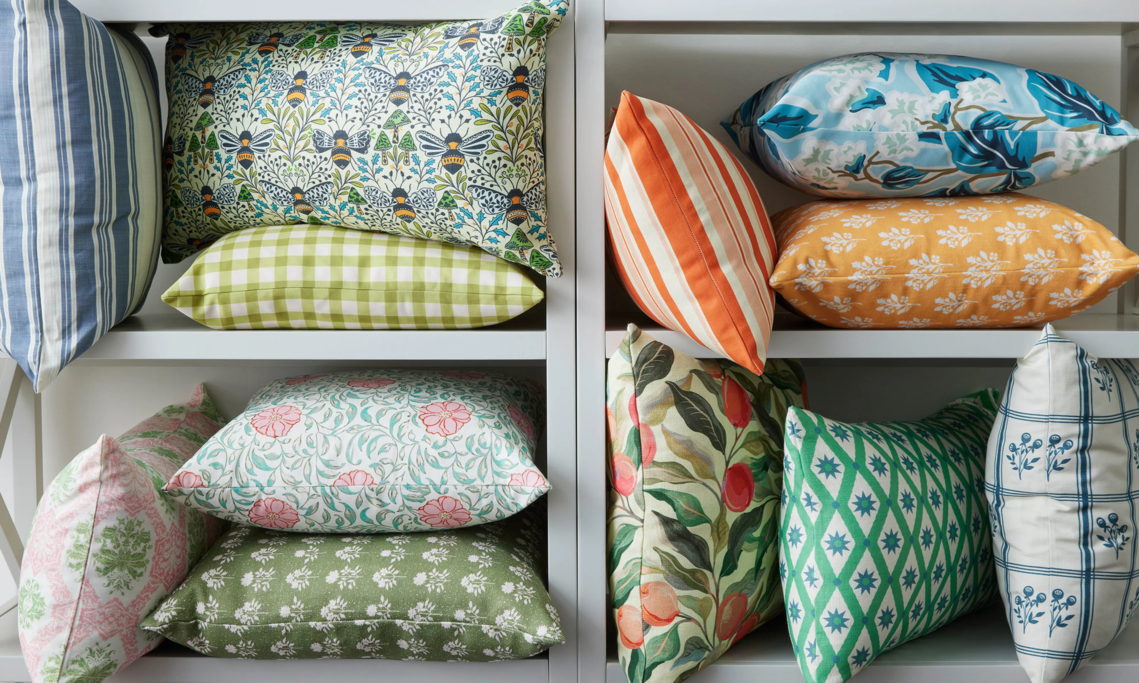 Shelf with many Spoonflower throw pillows all printed with unique patterns like floral, stripes, gingham and trellis.