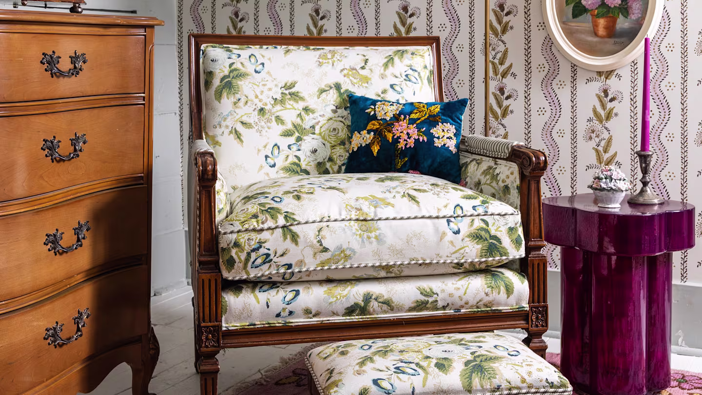 Wooden chair with upholstery of blue flowers and a small blue accent pillow.