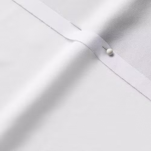 A close-up photo of white fabric with a pin running through it