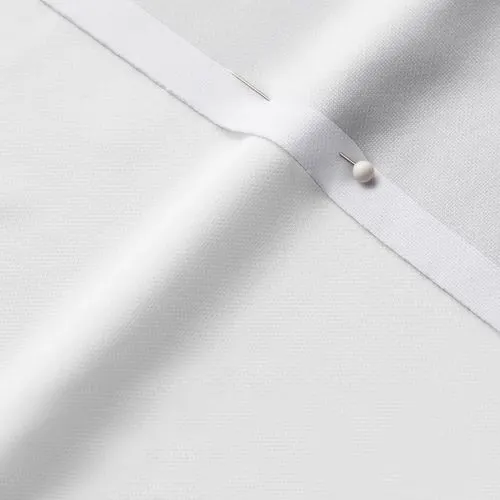 A close-up photo of white fabric with a pin running through it