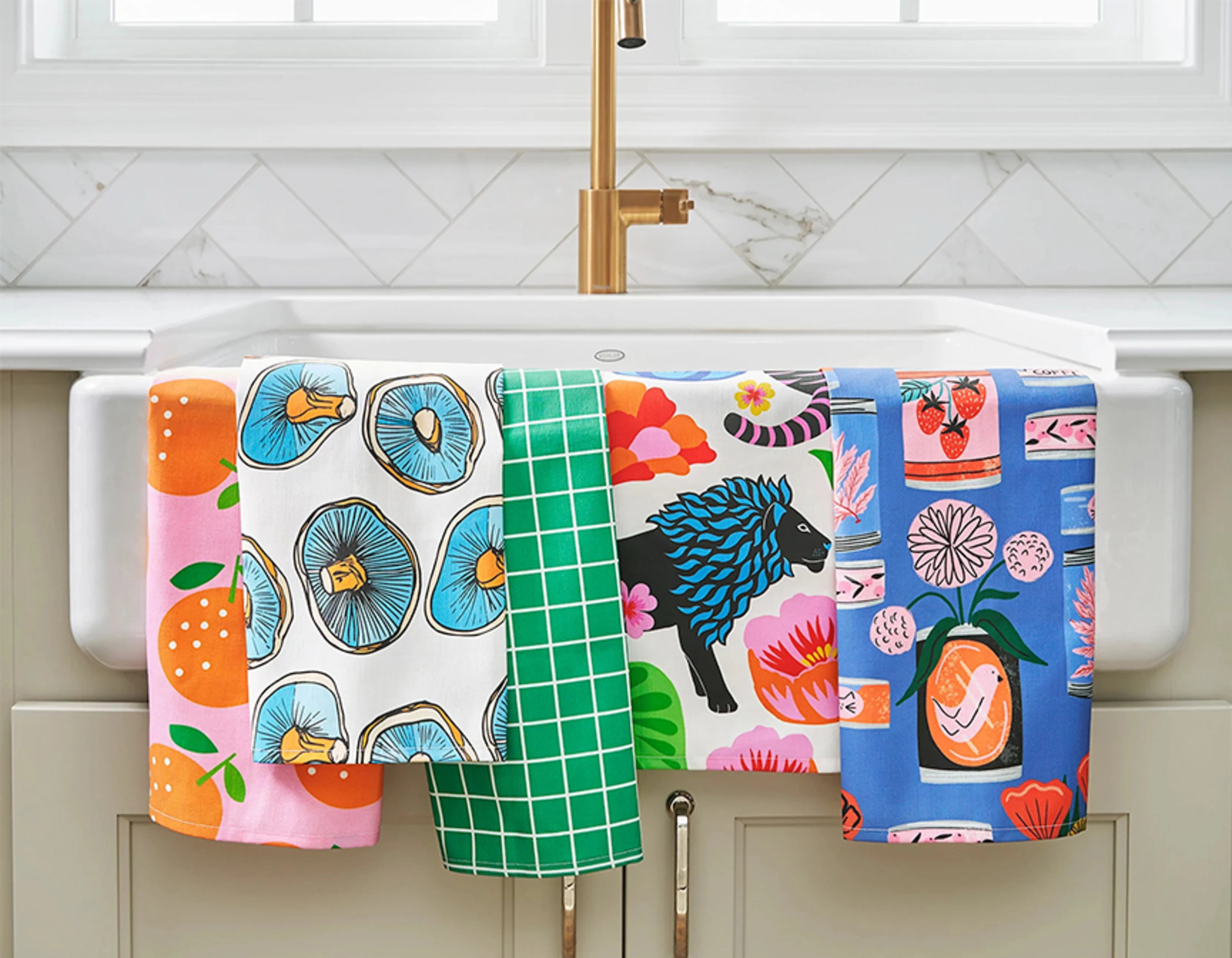 Multiple colorful tea towels hanging on kitchen sink.