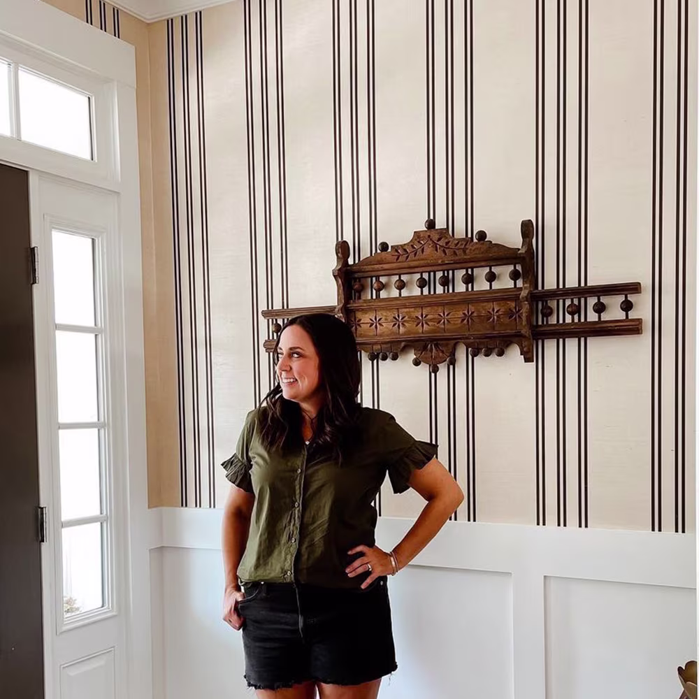 Woman posing in front of striped wallpaper entryway.
