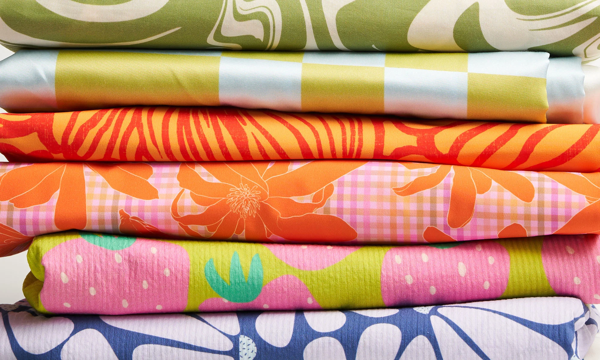 Stack of bright green and orange printed fabrics.