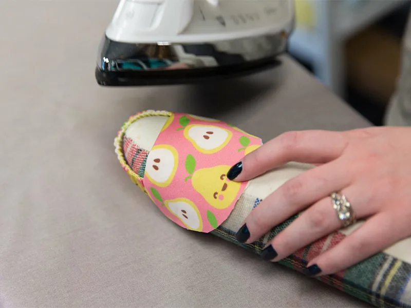 The sewn together heel and toe pieces are being pressed on a tailor's ham.