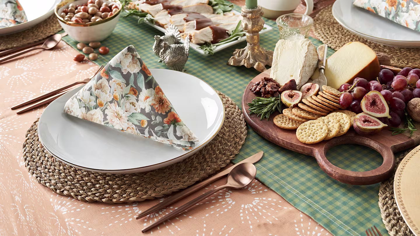 Green table runner over a peach table cloth and floral cloth napkins.