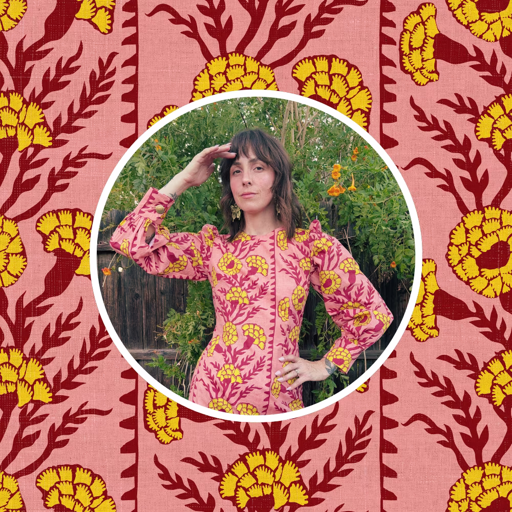Kelsey Garner in one of her handmade dresses in front of a bright pink and yellow boho Holli Zollinger design