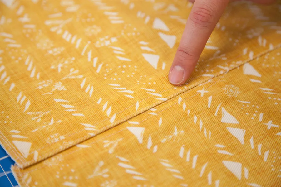 MaryAshlynn indicating the top stitch of her back vent on her skirt that is design side up.
