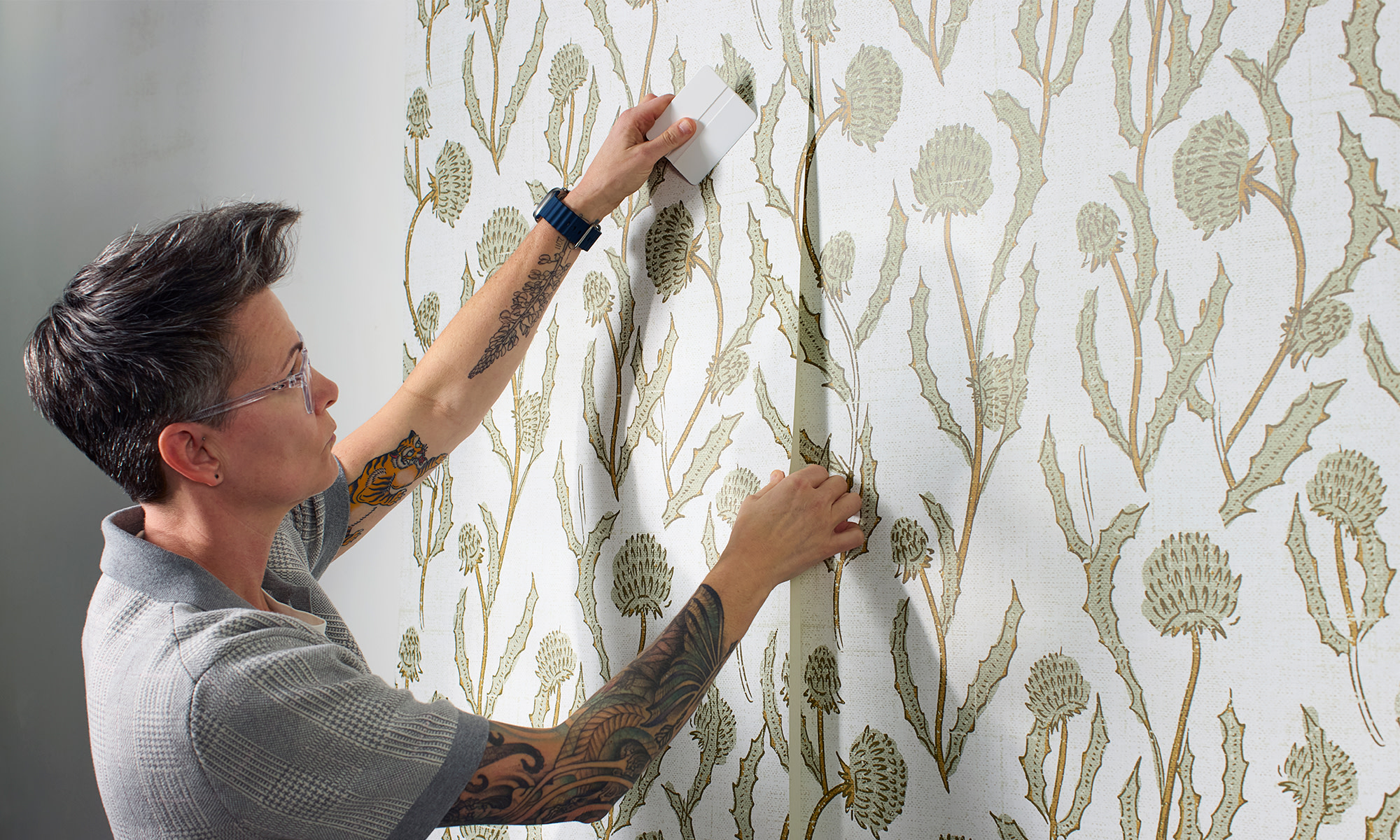 Person installing peel and stick wallpaper on a wall.