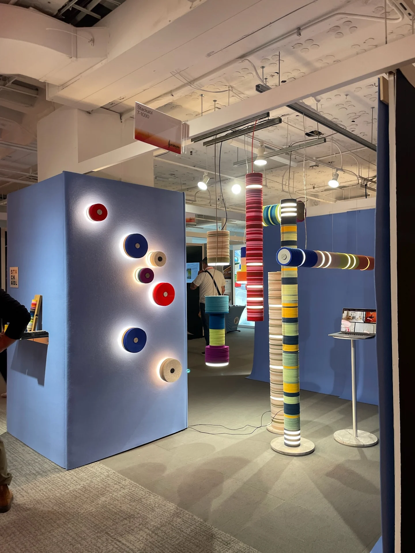 Colorful stacked textile discs forming illuminated pendant lights and wall fixtures in a modern showroom display