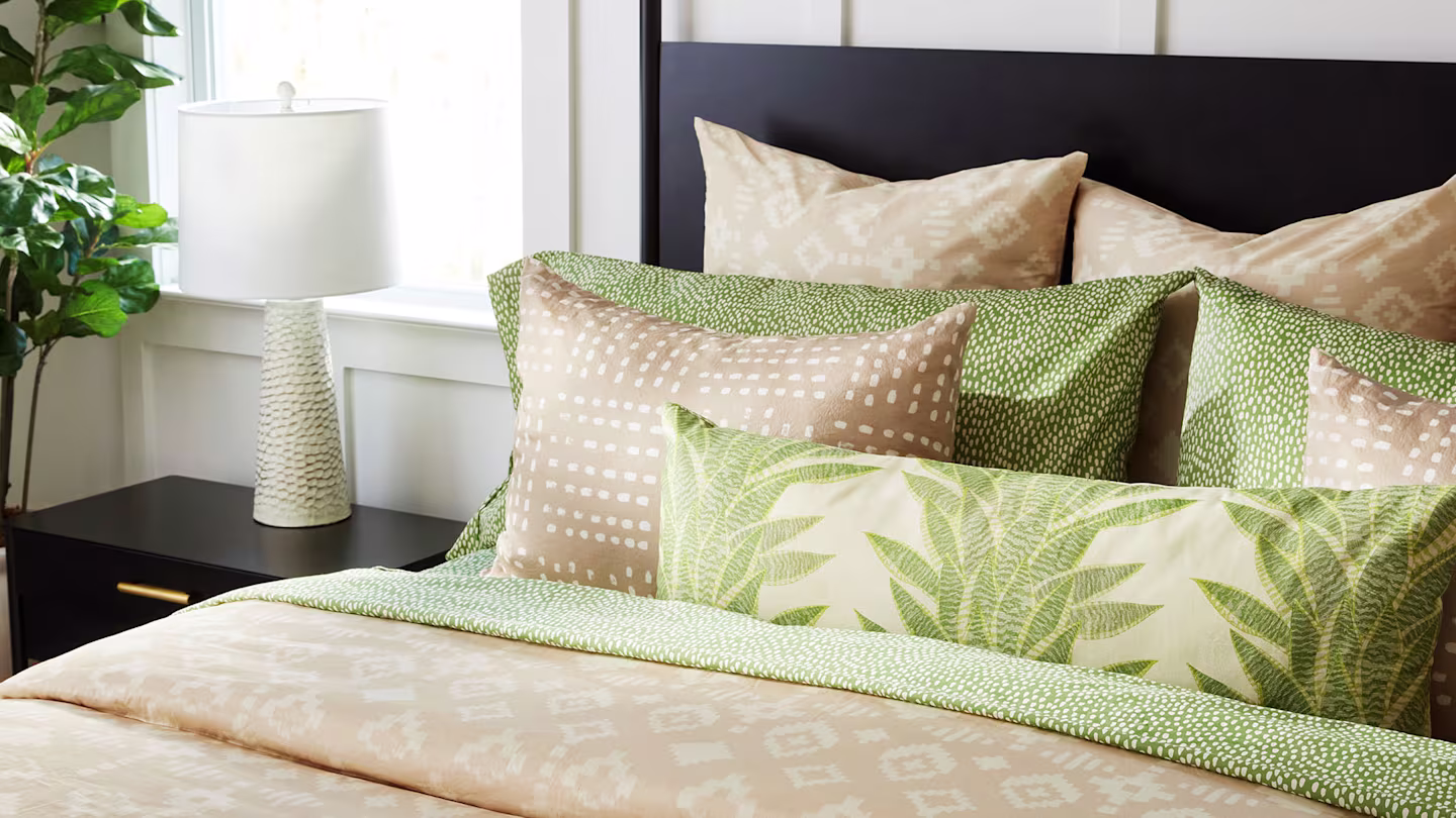 Bed wiith green and peach pillows.