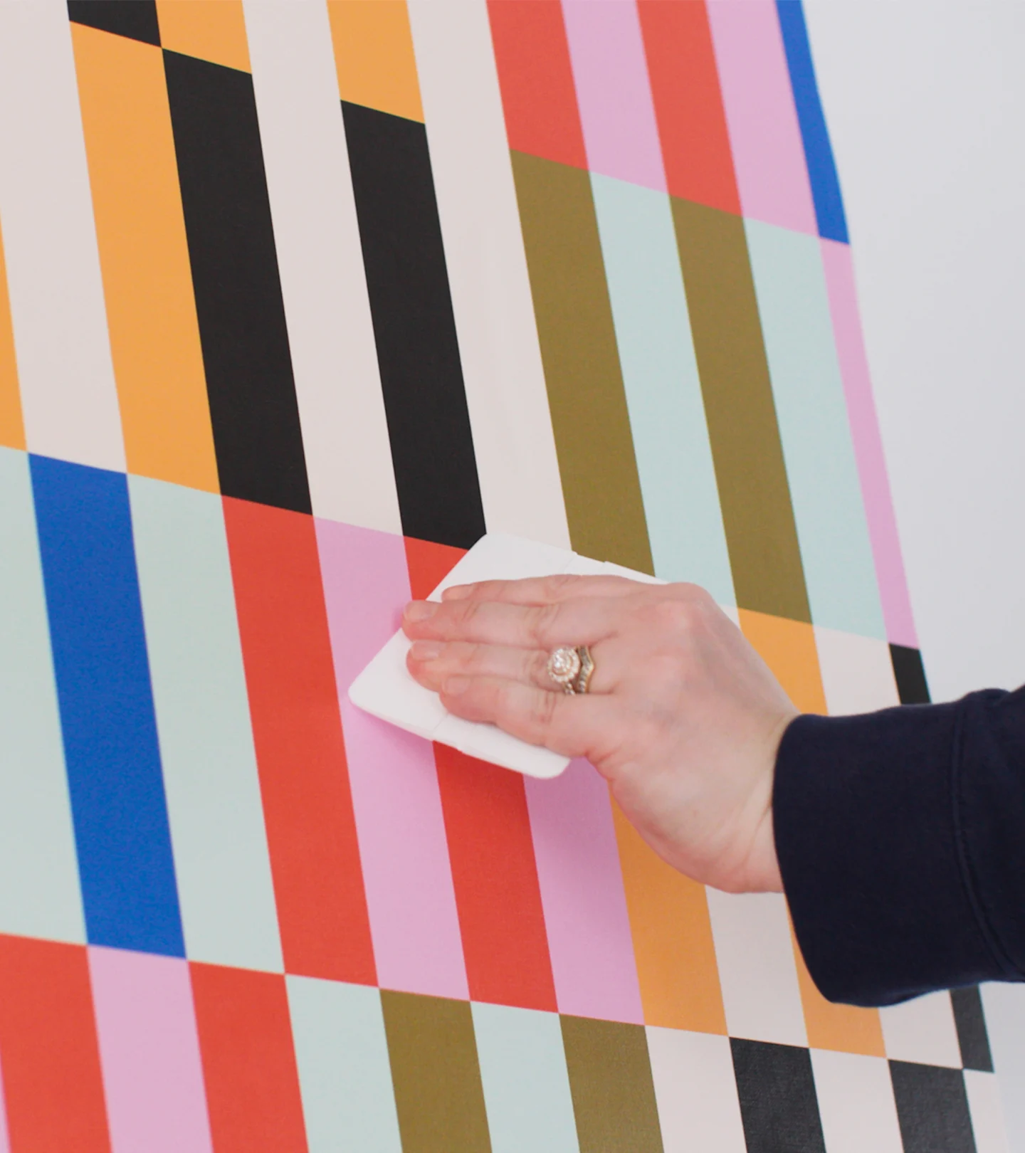 Person smoothing out peel and stick wallpaper.