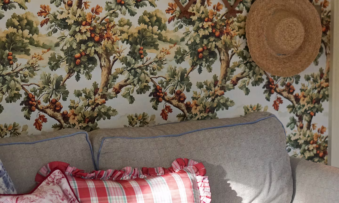 Couch in front of a wall that has oak tree wallpaper.