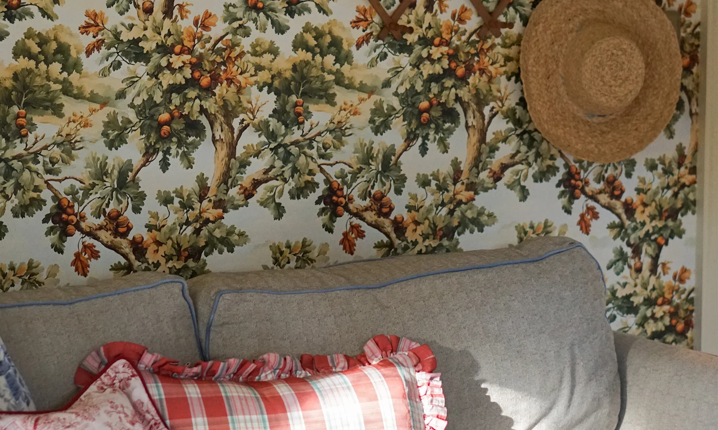 Couch in front of a wall that has oak tree wallpaper.