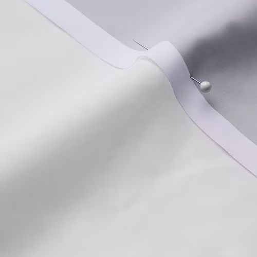 A close-up photo of white fabric with a pin running through it