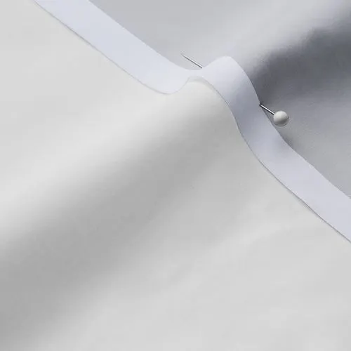 A close-up photo of white fabric with a pin running through it