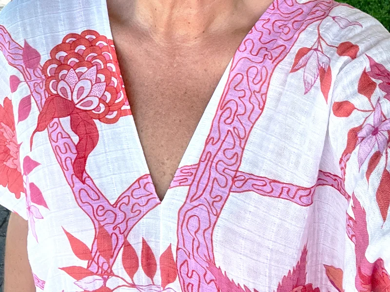 A close of the caftan's V neck. The pattern on the fabric features hot pink flowers on a white background.