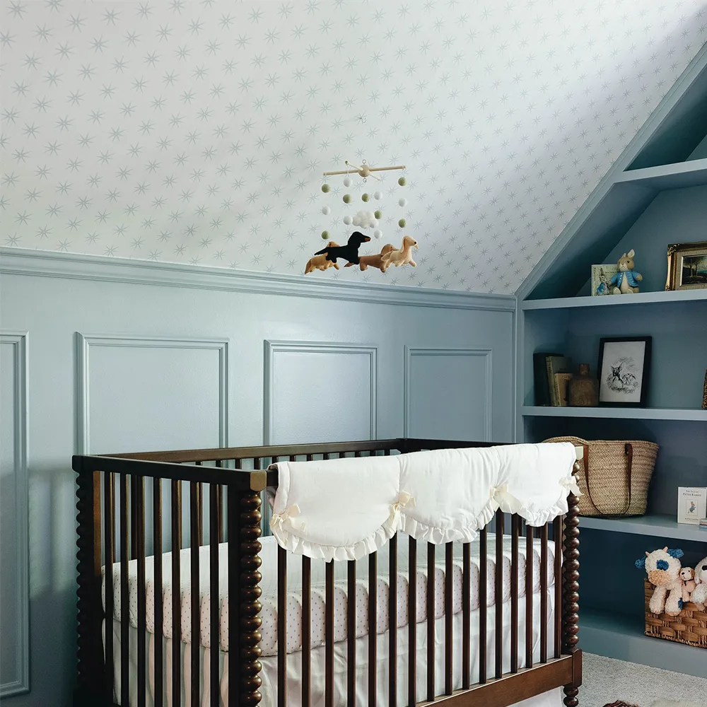 Nursery with blue star wallpaper on a slanted wall.
