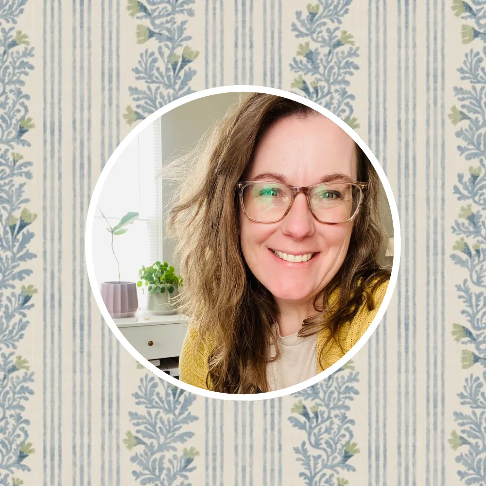 Headshot of artist jen owens in front of one of her designs.