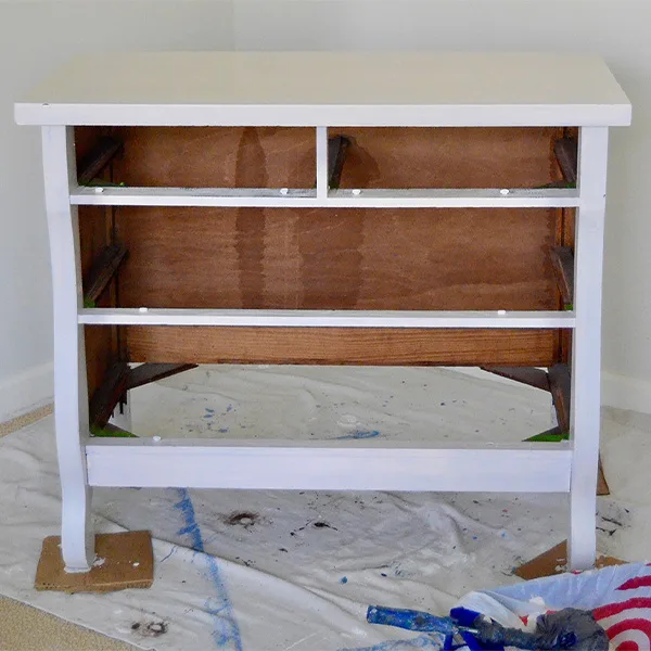 A white dresser with the shelves removed sits on a shop cloth in front of a white background.