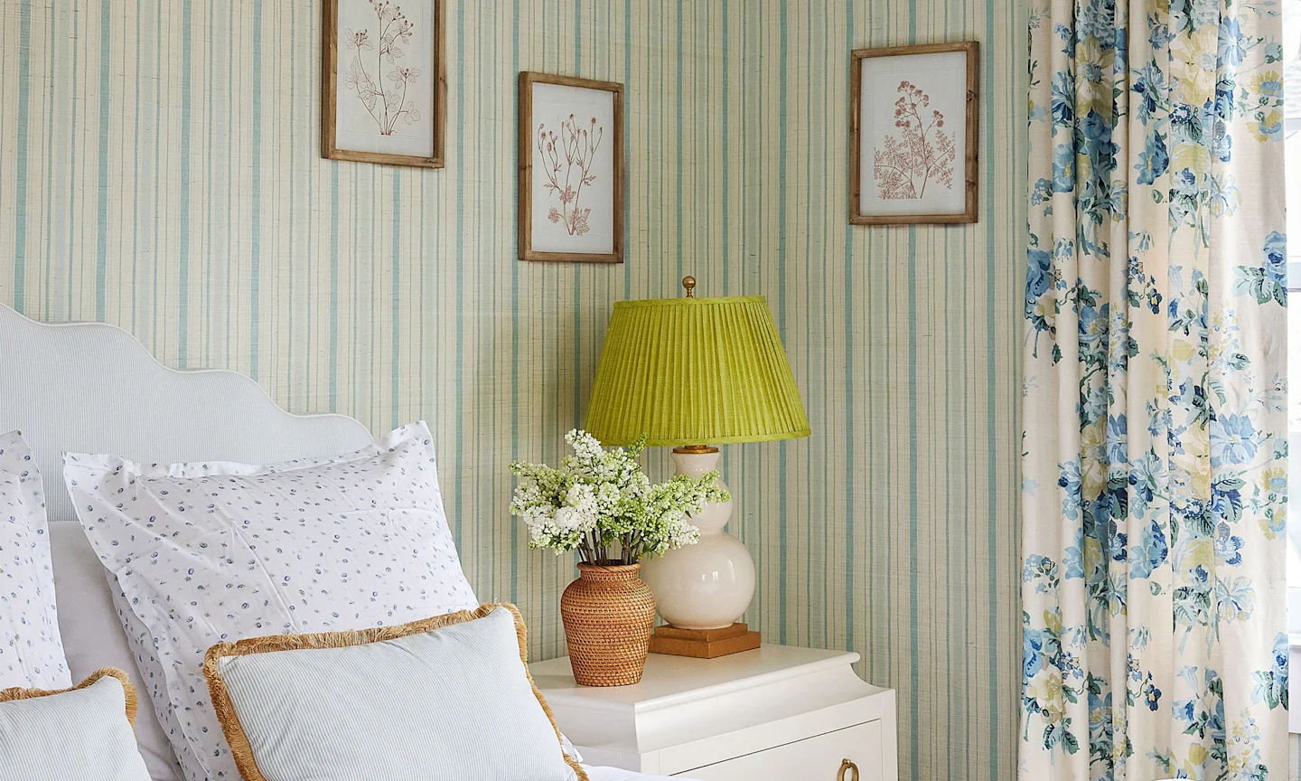 Bedroom with striped wallpaper and floral curtains.