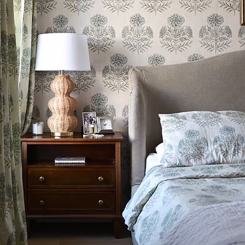 Floral bedding in a bedroom with nightstand and lamp