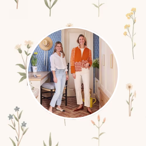 Molly Young and Jess Bauer of By Interiors in front of a small floral  design on a neutral background.