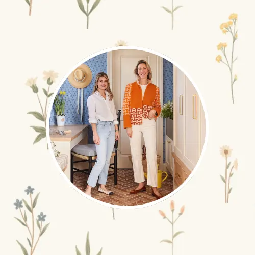Molly Young and Jess Bauer of By Interiors in front of a small floral  design on a neutral background.