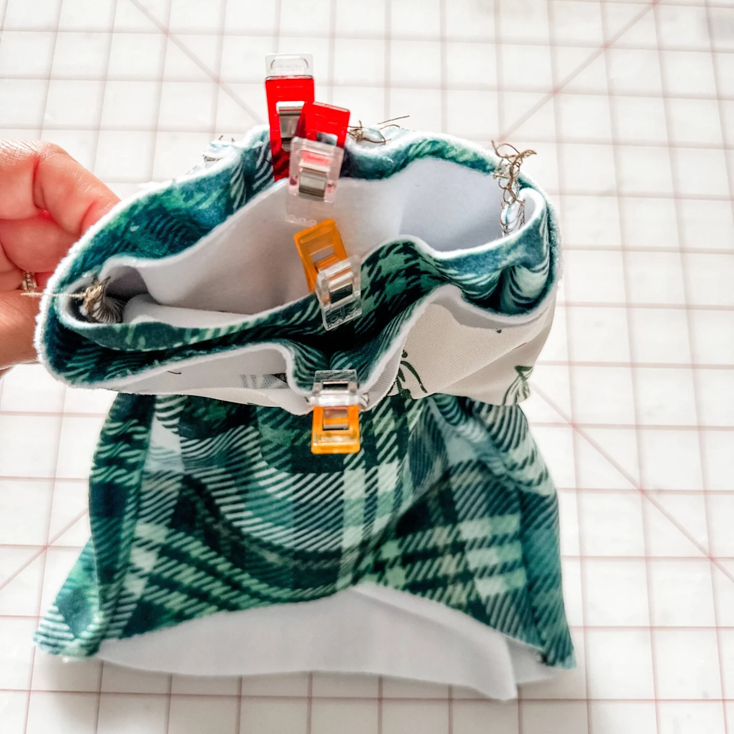 Stacie holds up the bodice and hoodie. The bodice has been pulled through the bottom of the hoodie piece. The sewing clips secure the bodice and hoodie from the center as we prepare to sew them together.