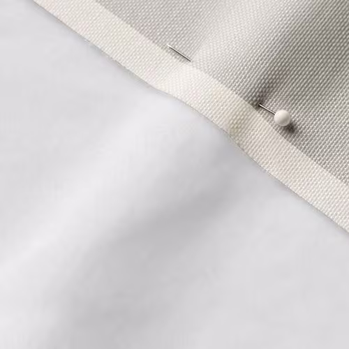 A close-up photo of white fabric with a pin running through it