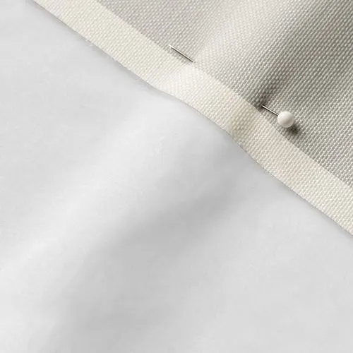 A close-up photo of white fabric with a pin running through it