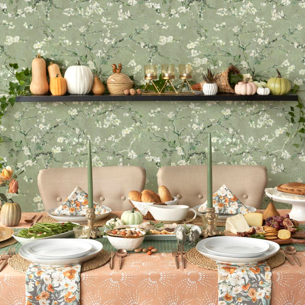 Orange and green harvest theme table setting against green botanical wallpaper