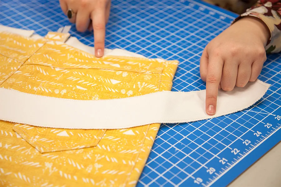 MaryAshlyn indicating where her interfacing will go on the waistband of her skirt by having one finger on the skirt, and the other on the interfacing.