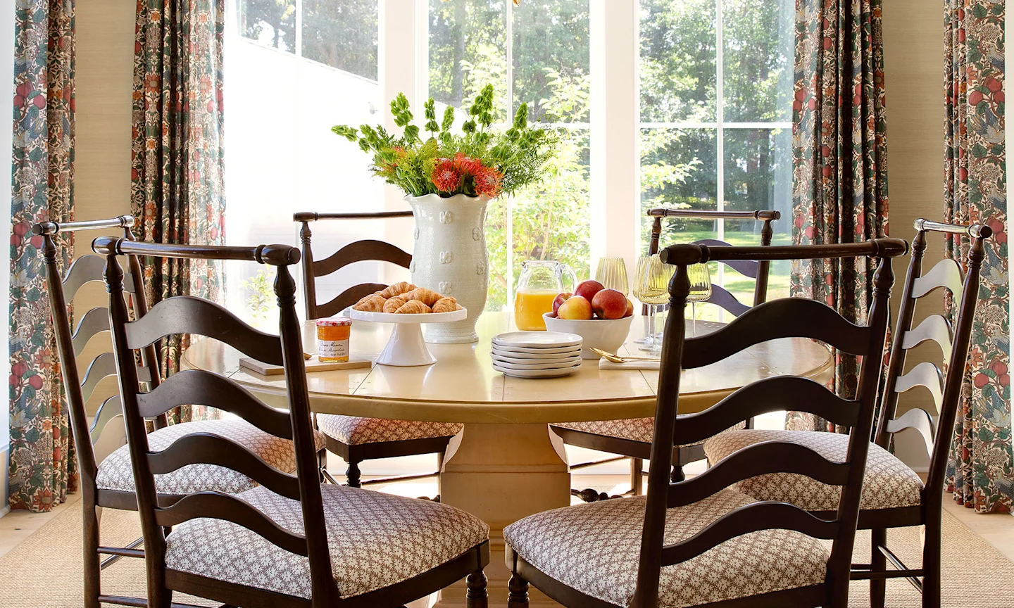 Dining room with a table, chair and curtains in the backdrop.