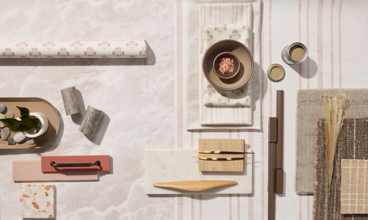 Rolls of neutral colored wallpapers on a tan background with decor items.